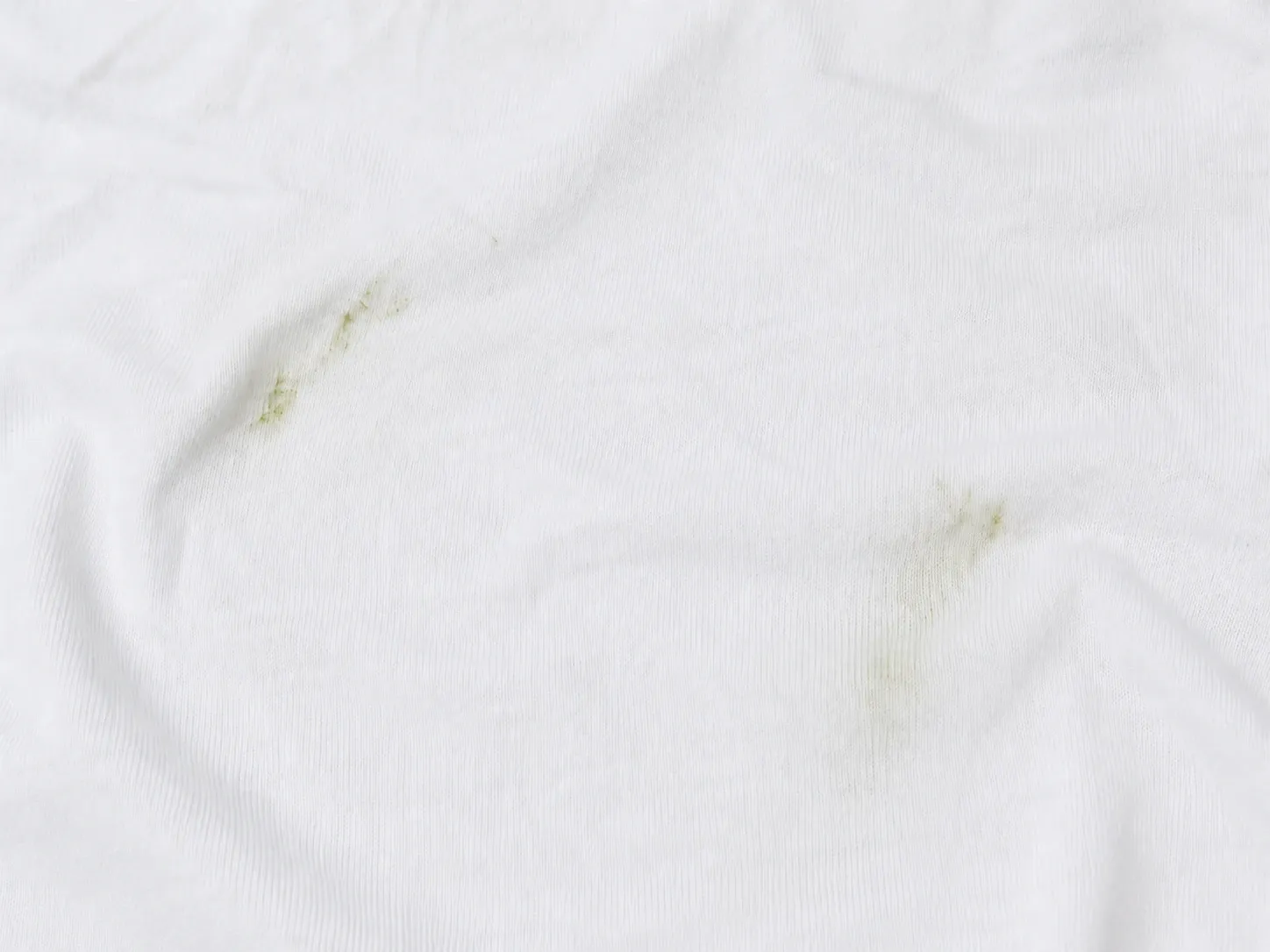 Zwei grüne Grasflecken auf einem weißen Baumwoll-T-Shirt