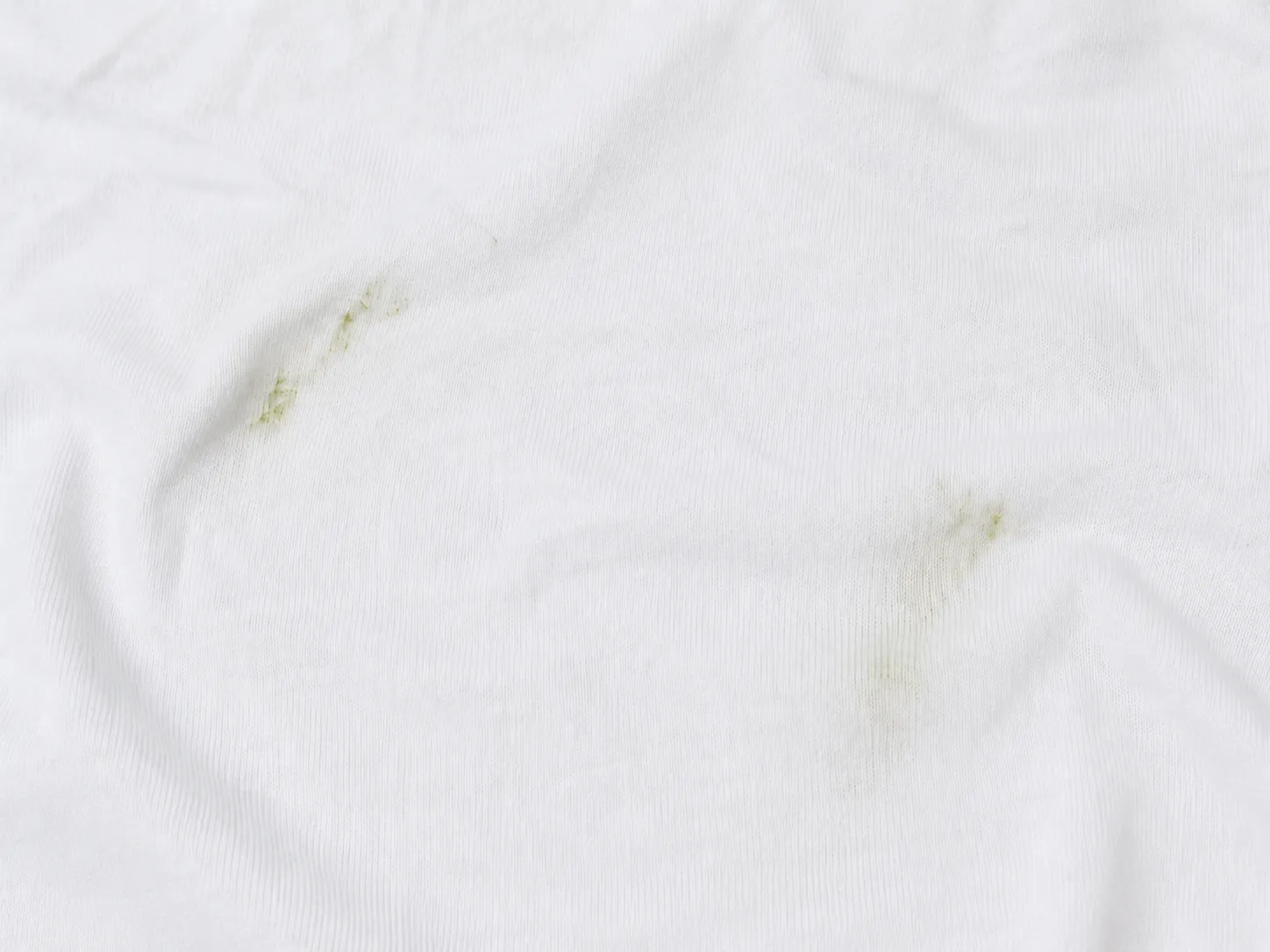 Zwei grüne Grasflecken auf einem weißen Baumwoll-T-Shirt