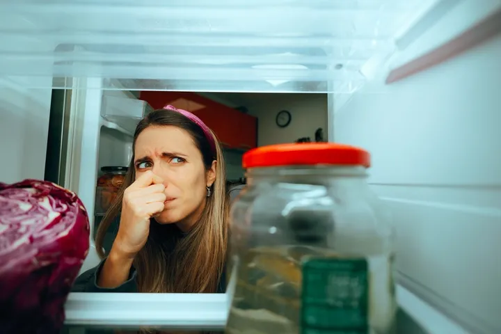 Kühlschranktür geöffnet mit Person, die sich die Nase zuhält